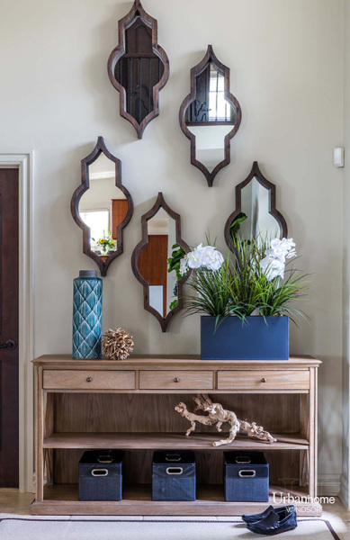 cascading mirror wall display over a console. wood sculpture features