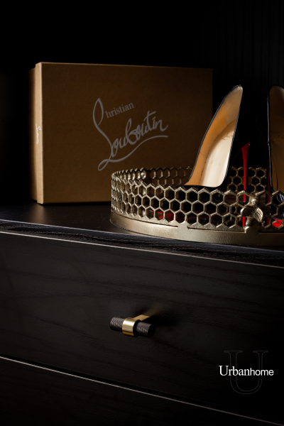 Close-up of a luxurious closet shelf featuring a pair of Christian Louboutin heels and a honeycomb metallic tray.
