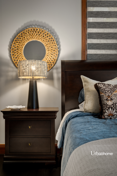 Bedside detail of a cozy bedroom with a dark wood nightstand and a modern lamp.