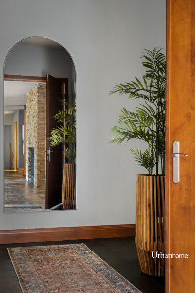 Entryway featuring a large arched mirror and a tall wooden planter holding lush greenery.