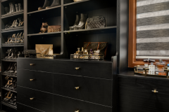 Chic walk-in closet with open shelving and drawers in dark wood finish.