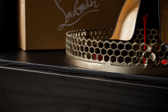 Close-up of a luxurious closet shelf featuring a pair of Christian Louboutin heels and a honeycomb metallic tray.