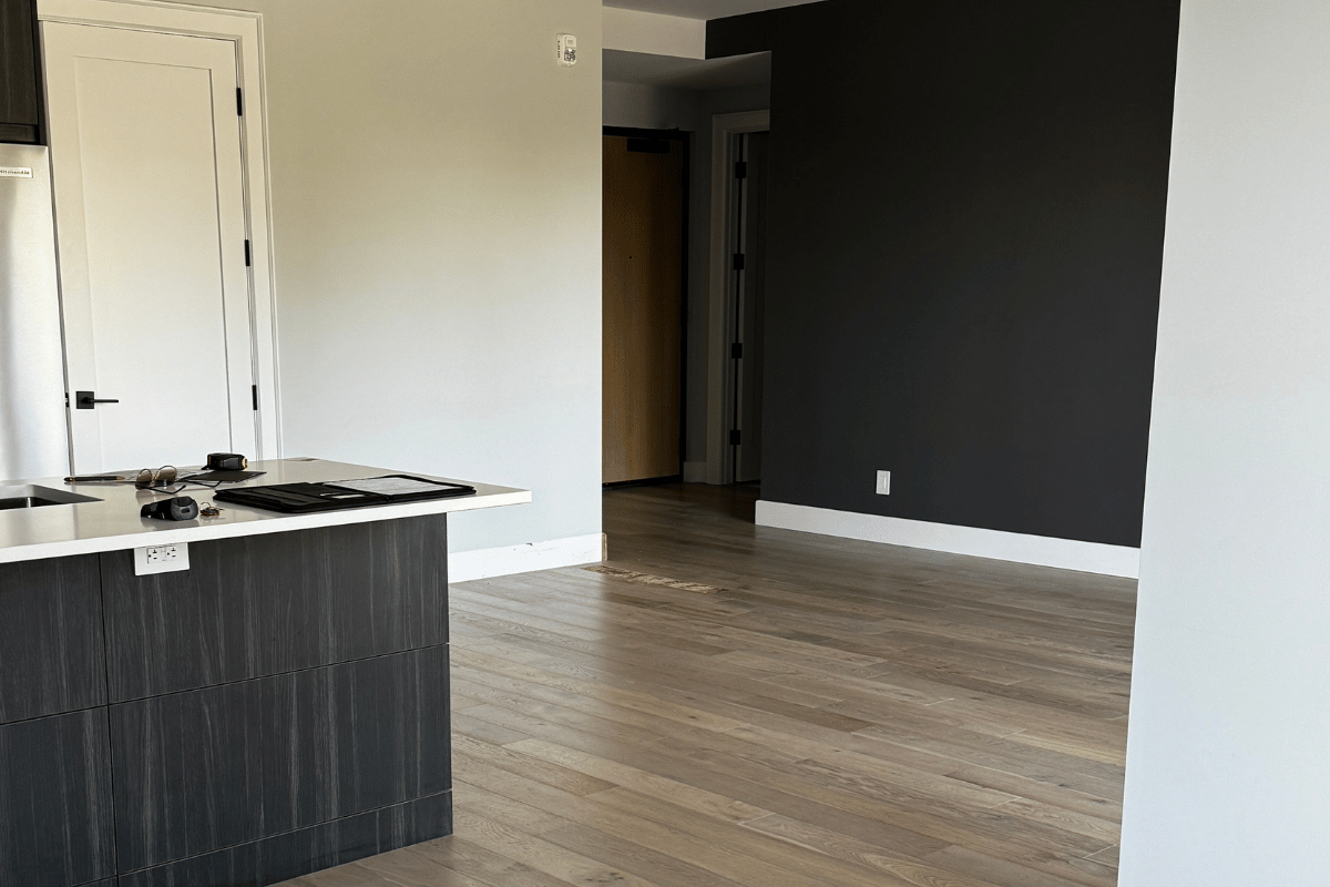 Before photo of a condo living room showing a dark feature wall, light flooring, and no furniture or decor.