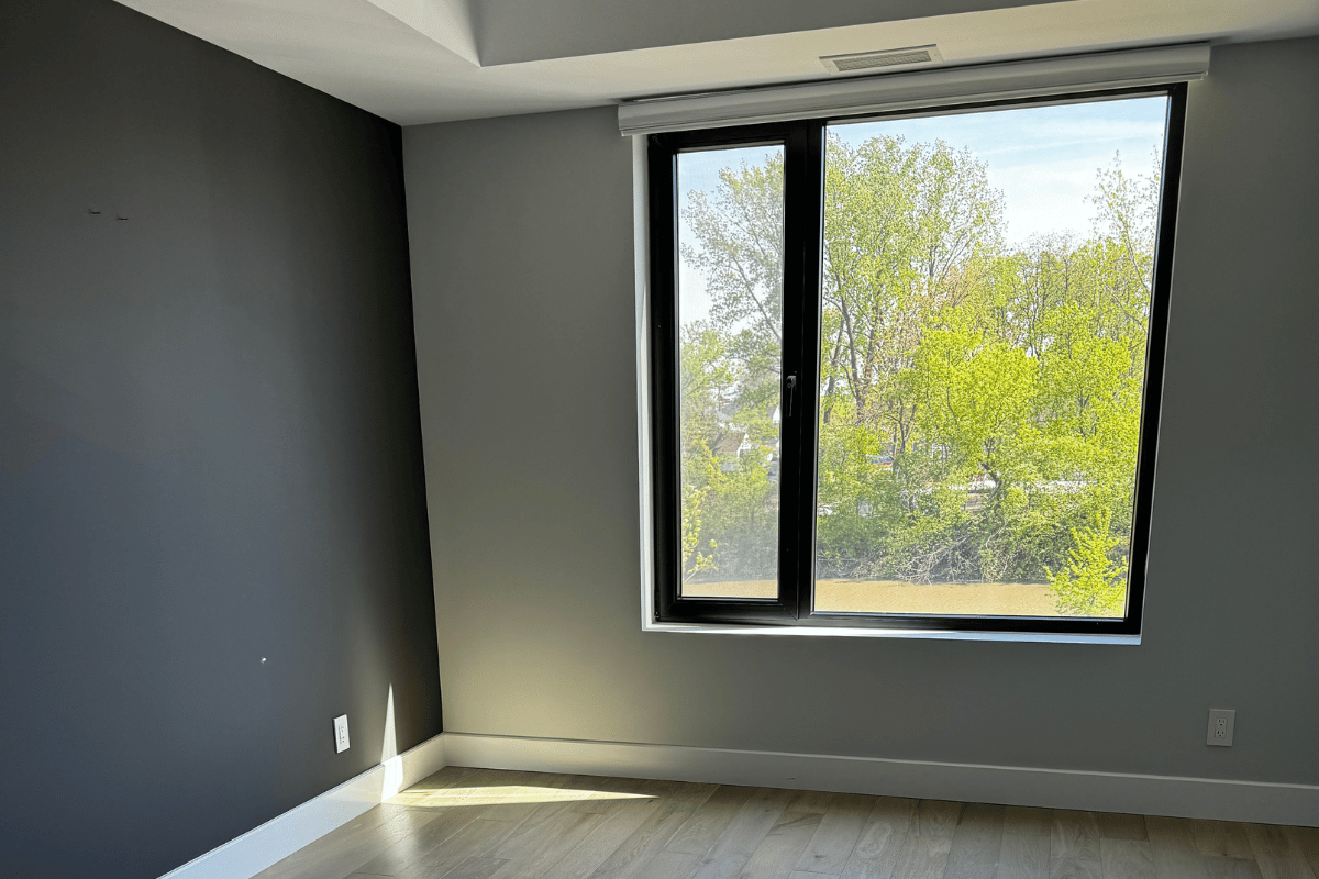 Empty grey-walled bedroom with large window and natural light before interior design transformation at Harbour Club Condo.