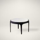 Pair of round nesting side tables with sculpted black metal frames and white marble tops, styled in front of a sectional in a bright living room.
