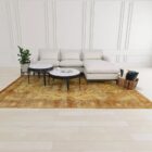 Pair of round nesting side tables with sculpted black metal frames and white marble tops, styled in front of a sectional in a bright living room.