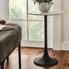Round accent table with a sculptural black pedestal base and a smooth white marble top, shown in product detail, lifestyle, and material close-ups.