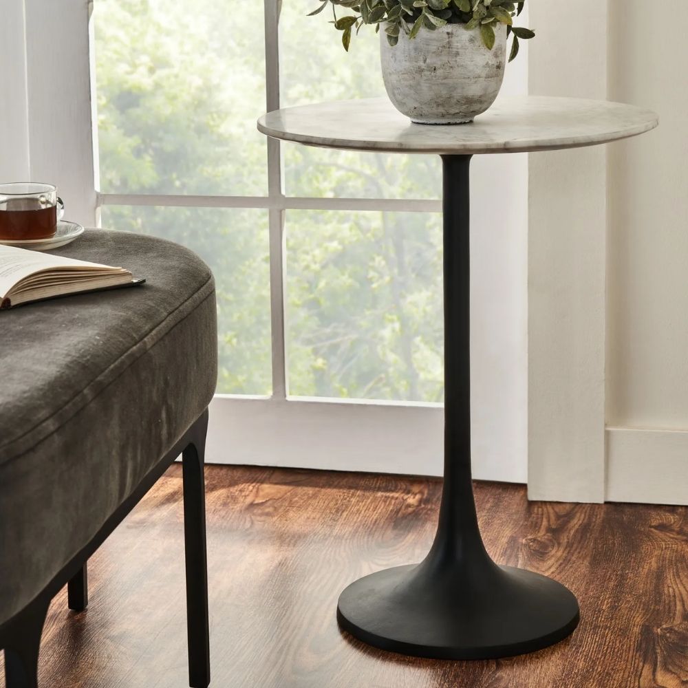 Round accent table with a sculptural black pedestal base and a smooth white marble top, shown in product detail, lifestyle, and material close-ups.