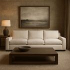 Contemporary low-profile sofa in soft white fabric with boxy arms and plush cushions, shown in product and styled living room views.