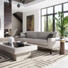 Oval black stone-topped side table with a flared wood base and brass detailing, styled next to a modern sofa in a sunlit living room.
