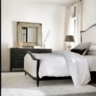 Black six-drawer dresser with brass knobs and lightly distressed finish.