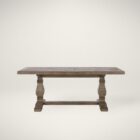 Rustic rectangular dining table with a thick wooden top and two carved pedestal legs connected by a stretcher base.