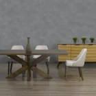 Modern rectangular dining table with a warm wood finish and an angular starburst pedestal base.