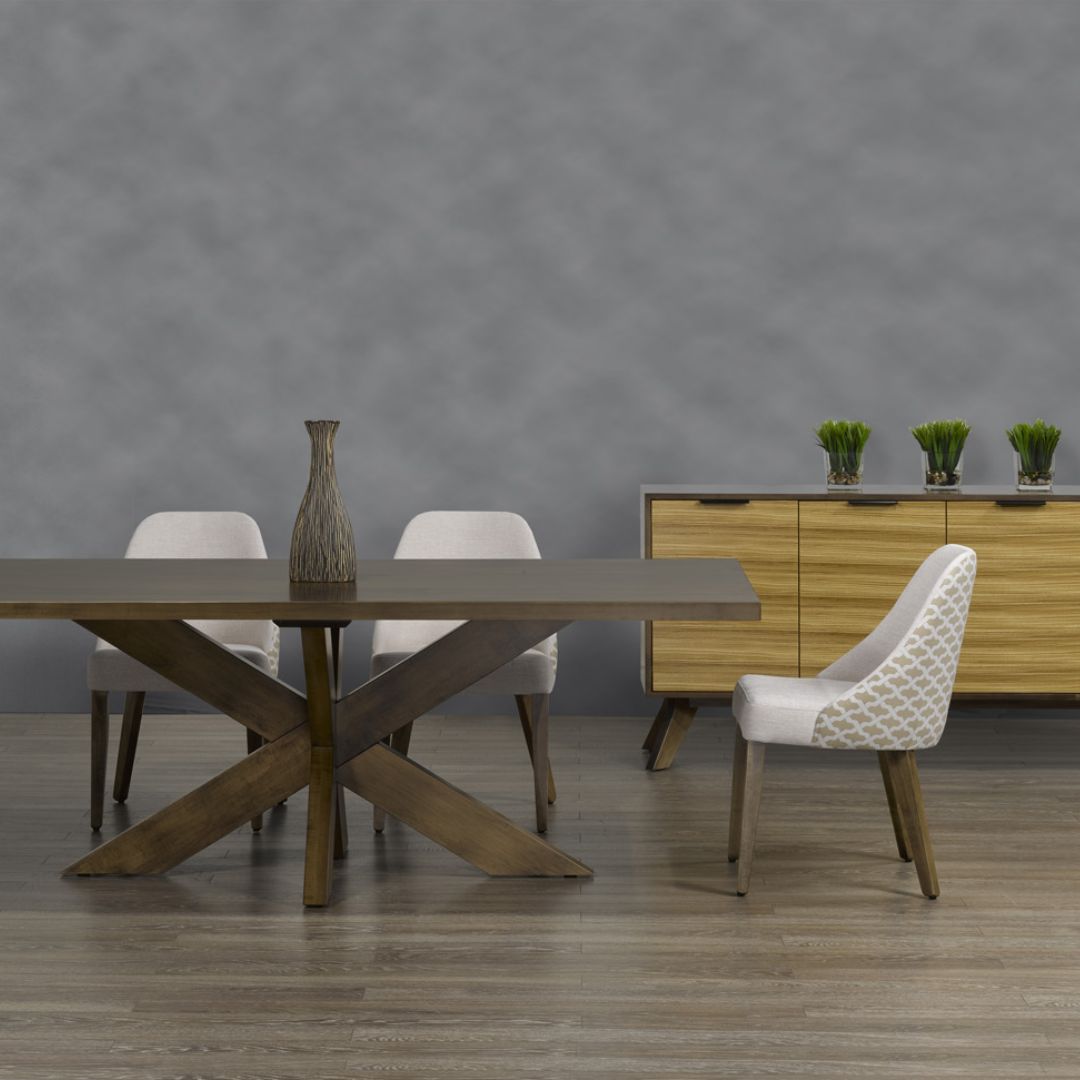 Modern rectangular dining table with a warm wood finish and an angular starburst pedestal base.