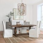 Rustic rectangular dining table with a thick wooden top and two carved pedestal legs connected by a stretcher base.