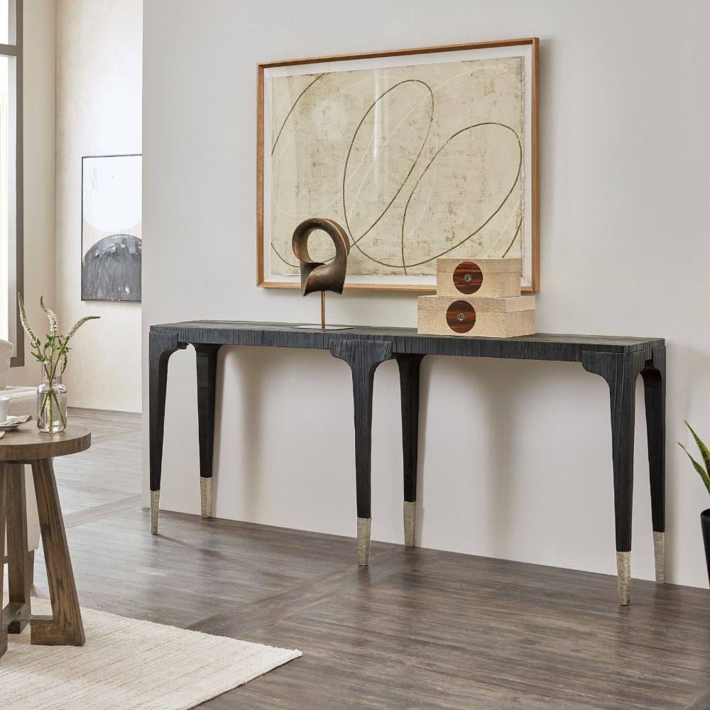 Long black wood console table with sculpted legs and metallic foot caps, finished in a Shou Sugi Ban burnished texture