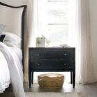 Black distressed wood two-drawer nightstand with tapered legs and rounded drawer fronts.