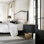 Black distressed wood two-drawer nightstand with tapered legs and rounded drawer fronts.
