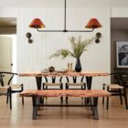 Rectangular live-edge wood dining table with a natural finish and matte black metal cross-frame legs.