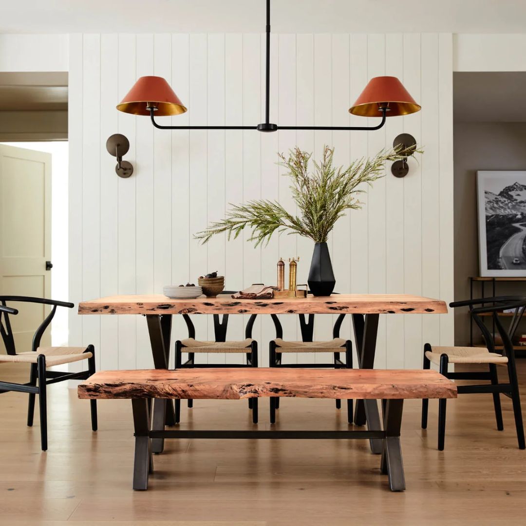 Rectangular live-edge wood dining table with a natural finish and matte black metal cross-frame legs.