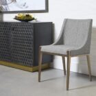 A contemporary dining chair with a curved high backrest and sleek, tailored lines in textured grey upholstery over a taupe wood frame.