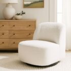 Minimalist white boucle swivel chair with soft curves and black base.