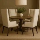 A high-back, upholstered dining chair with wingback arms, straight profile, and a dark wood leg frame.