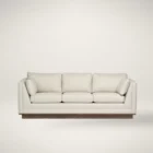 Contemporary cream-colored sofa with structured arms, three back cushions, and a recessed wood base.