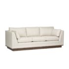 Contemporary cream-colored sofa with structured arms, three back cushions, and a recessed wood base.