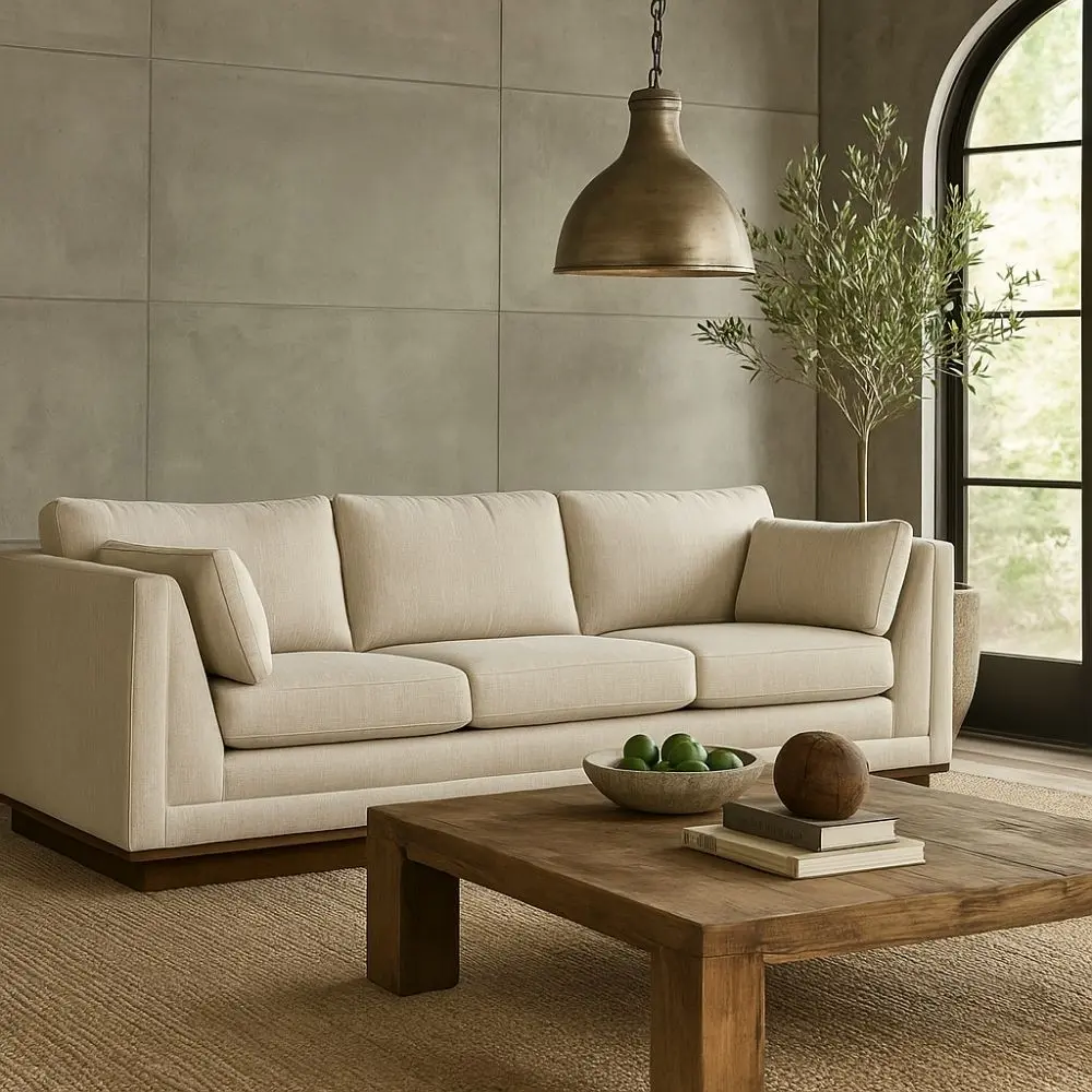 Contemporary cream-colored sofa with structured arms, three back cushions, and a recessed wood base.