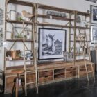 Tall industrial-style shelving unit with metal frame, wood shelves, integrated bottom drawers, and a leaning metal ladder.