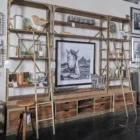 Tall industrial-style shelving unit with metal frame, wood shelves, integrated bottom drawers, and a leaning metal ladder.