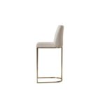 A modern upholstered counter stool with a curved brass-finished metal base and light neutral fabric seat and back.
