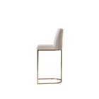 A modern upholstered counter stool with a curved brass-finished metal base and light neutral fabric seat and back.
