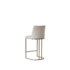 A modern upholstered counter stool with a curved brass-finished metal base and light neutral fabric seat and back.