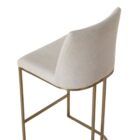 A modern upholstered counter stool with a curved brass-finished metal base and light neutral fabric seat and back.