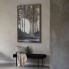 Framed wall art depicting a moody forest landscape in muted tones of green, grey, and white with a reflective water foreground.