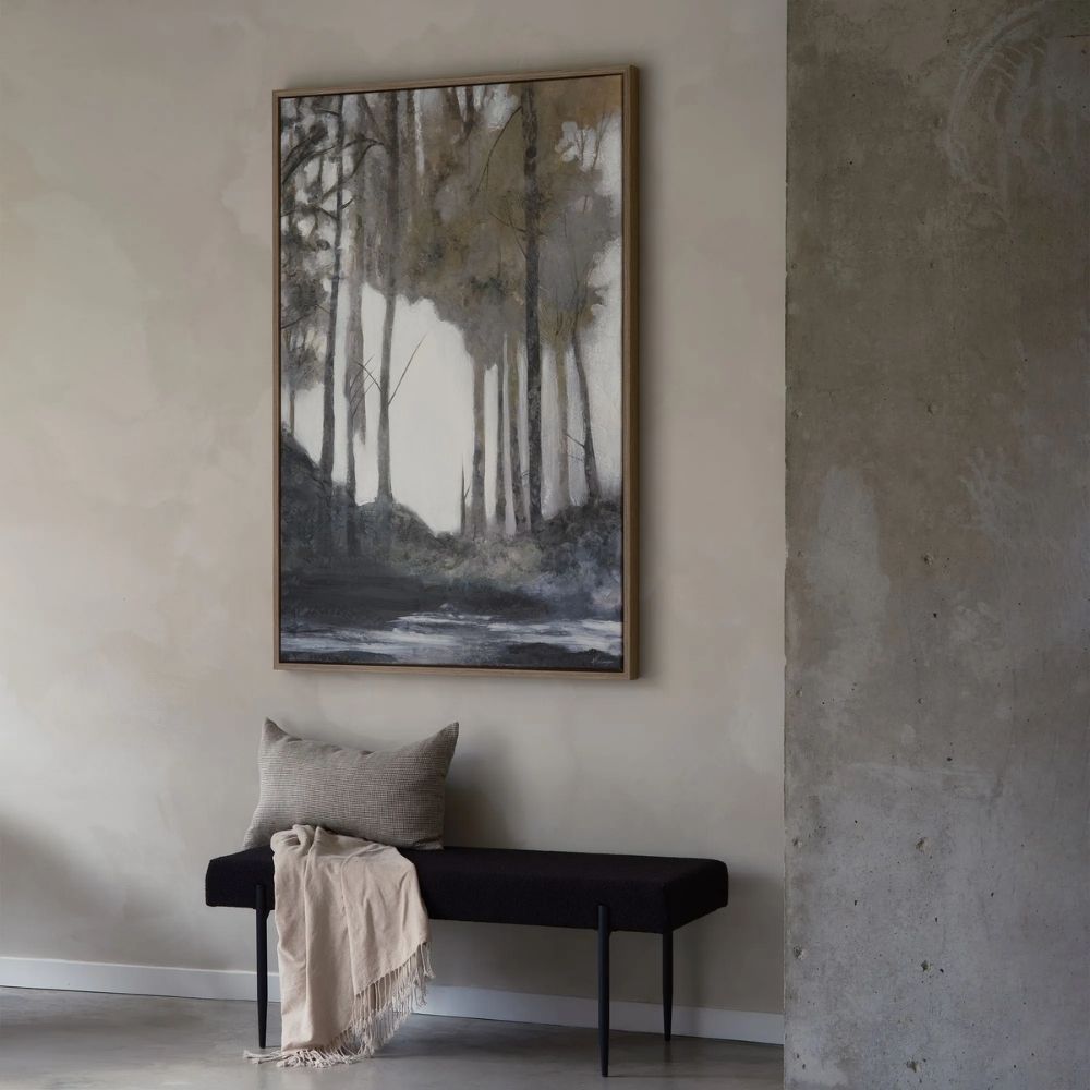 Framed wall art depicting a moody forest landscape in muted tones of green, grey, and white with a reflective water foreground.