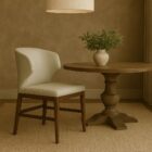 Amed Stretcher Dining Chair featuring a curved cream upholstered backrest and walnut wood frame with horizontal stretcher support.