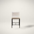 A modern upholstered counter stool with a soft cream fabric seat and backrest, wooden trim, and sleek black metal legs.