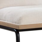 A modern upholstered counter stool with a soft cream fabric seat and backrest, wooden trim, and sleek black metal legs.
