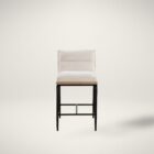 A modern upholstered counter stool with a soft cream fabric seat and backrest, wooden trim, and sleek black metal legs.