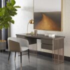 Modern barrel-back dining armchair with charcoal grey fabric seat, faux leather exterior, black tapered legs, and brass metal caps.
