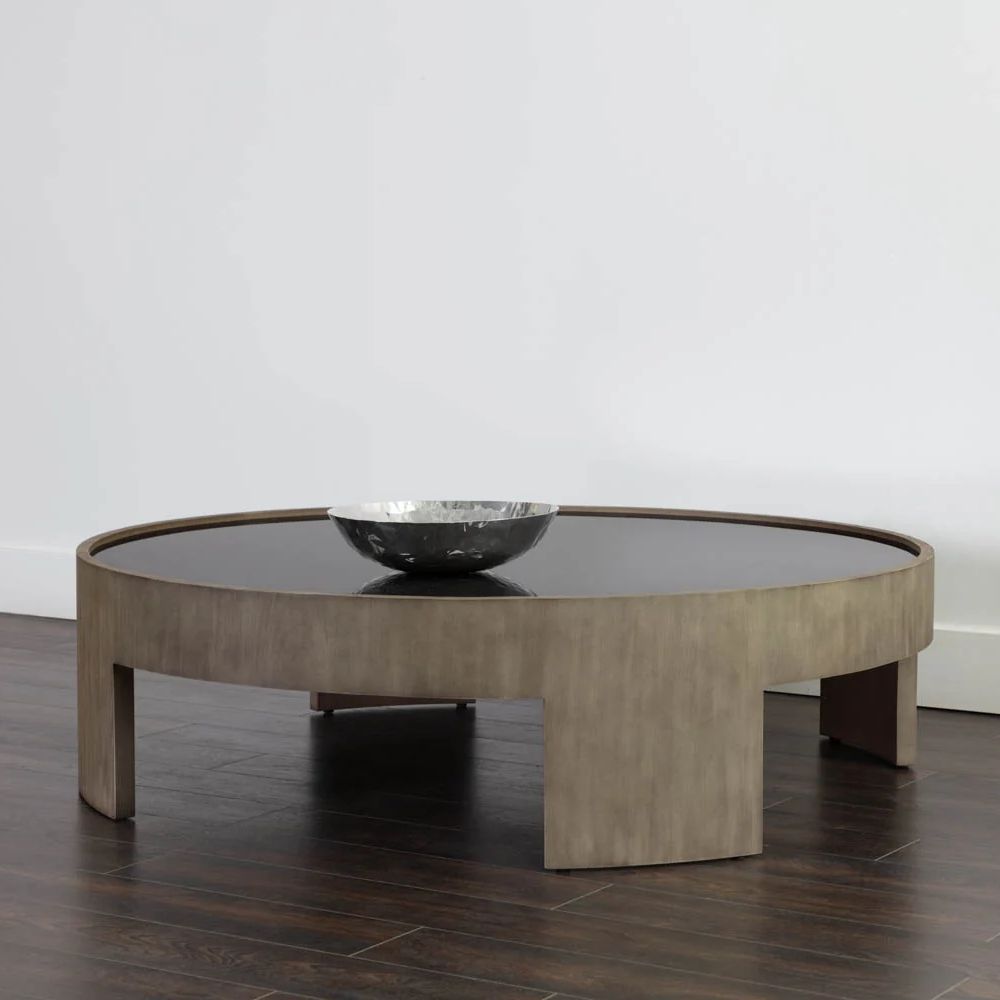Round coffee table with light wood base and dark recessed top, featuring sculptural curved legs.