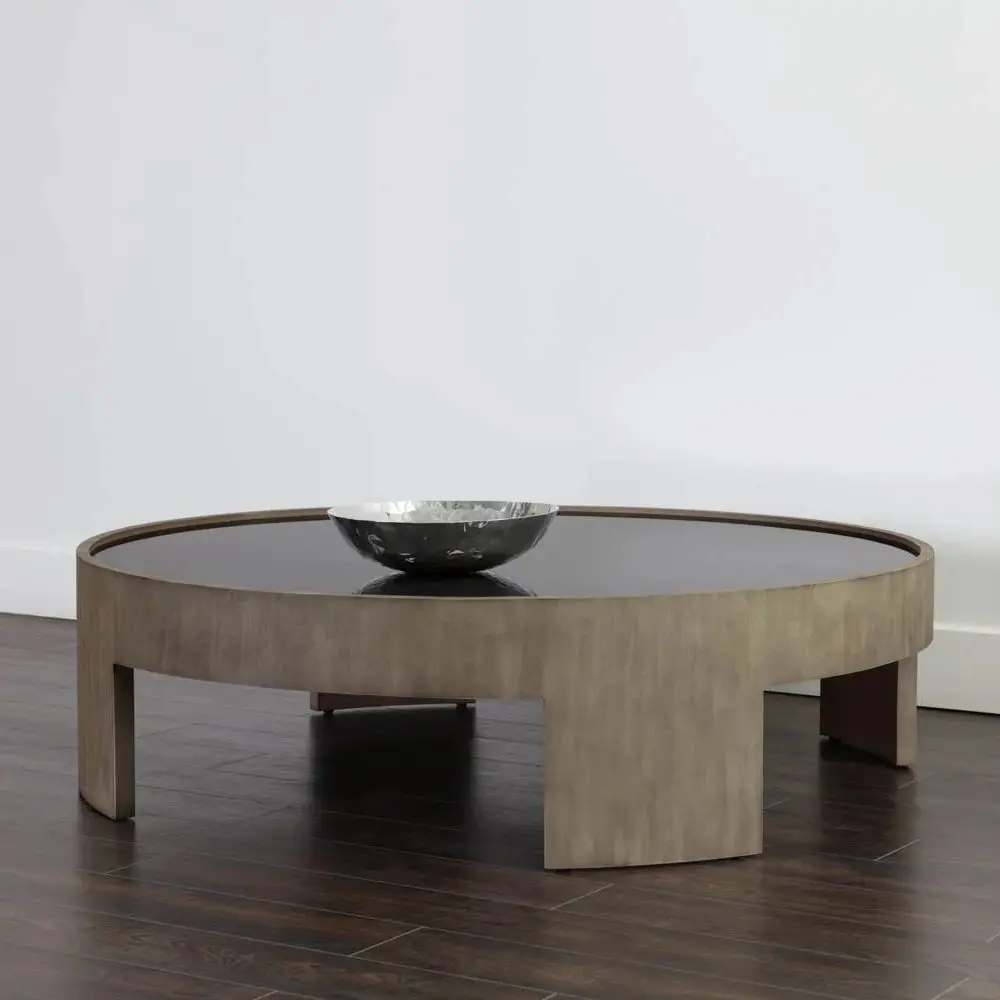 Round coffee table with light wood base and dark recessed top, featuring sculptural curved legs.