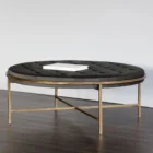 Round tufted ottoman with charcoal black upholstery and slender antique brass base frame.