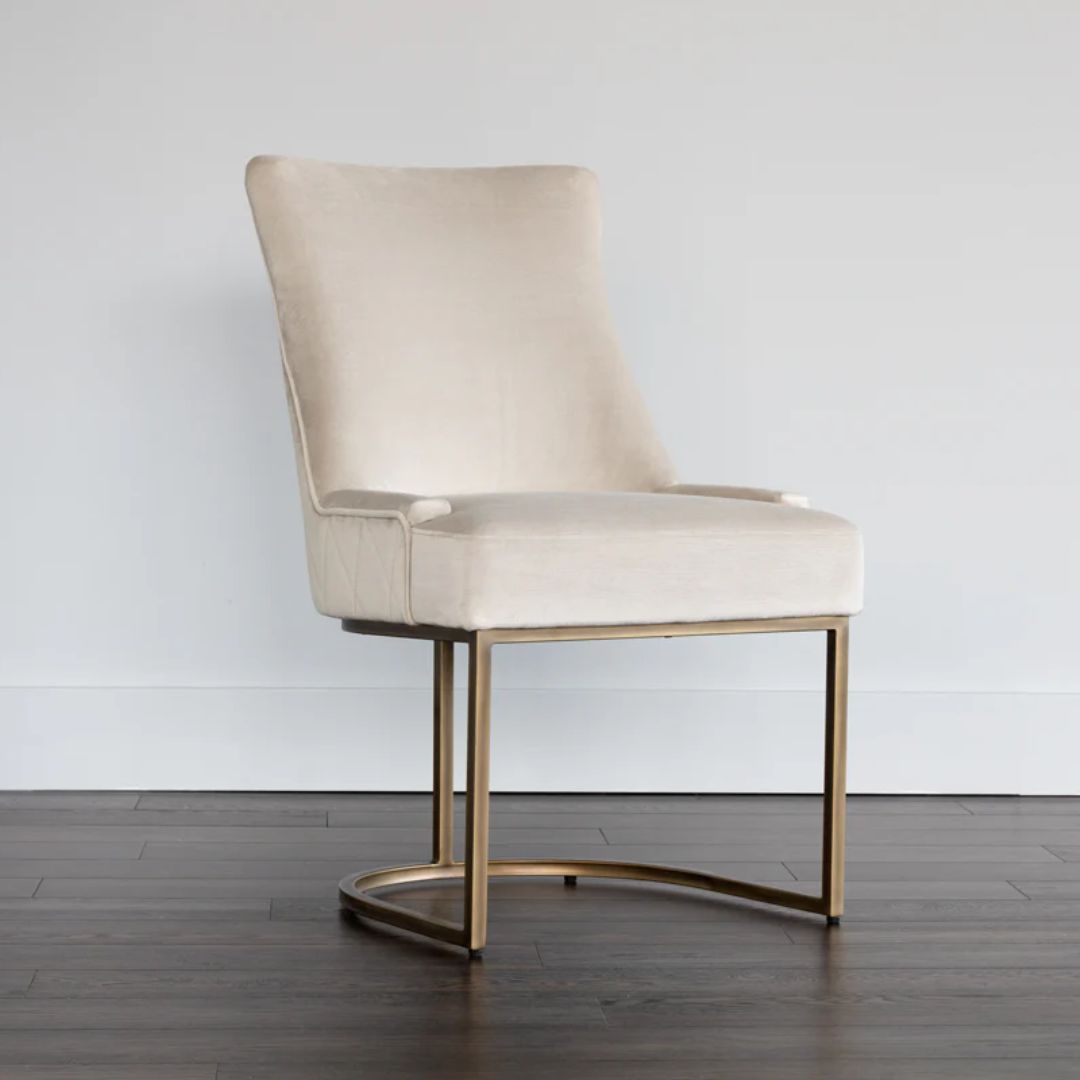 Elegant stool with soft beige upholstered seat and curved gold metal base.