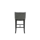 Dark grey upholstered barstool with low backrest and black wooden legs, styled beside a light wood countertop in a neutral-toned interior.