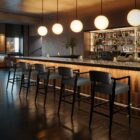 A modern barstool with black wood frame, dark leather upholstery, and a low backrest.