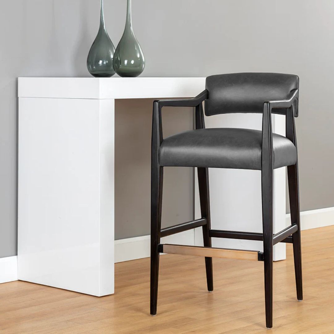 A modern barstool with black wood frame, dark leather upholstery, and a low backrest.